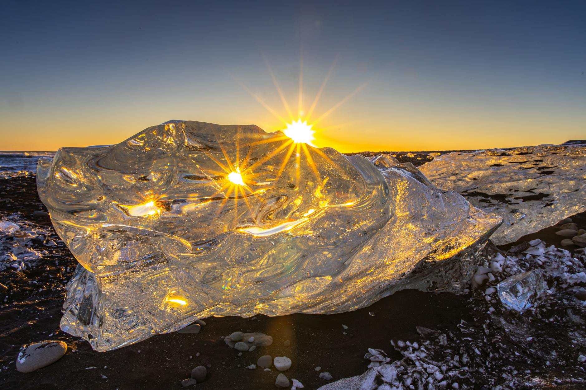 mesmerizing sunrise behind ice block on icelandic beach