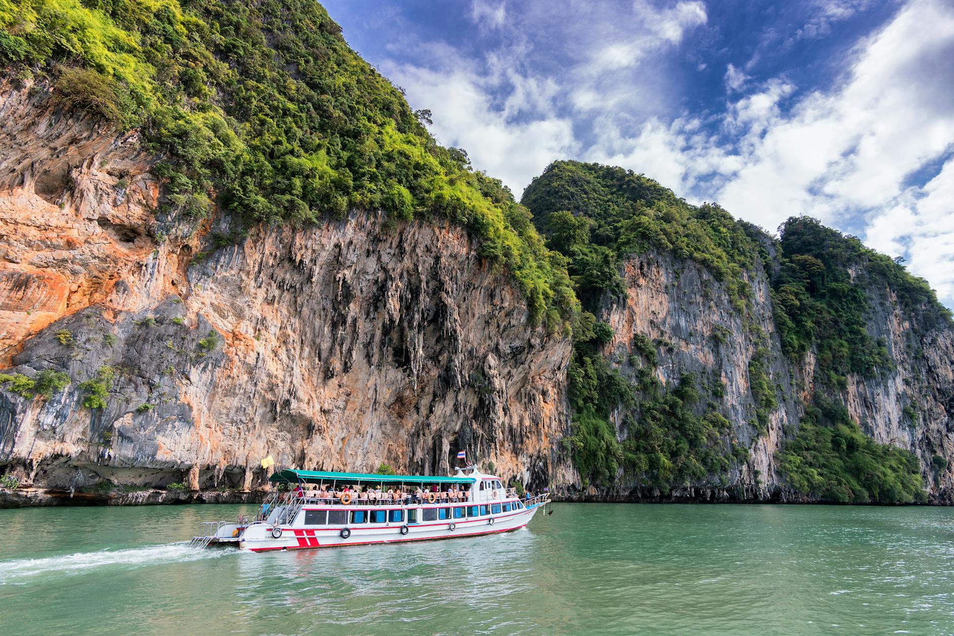 people on ship traveling on water beside land