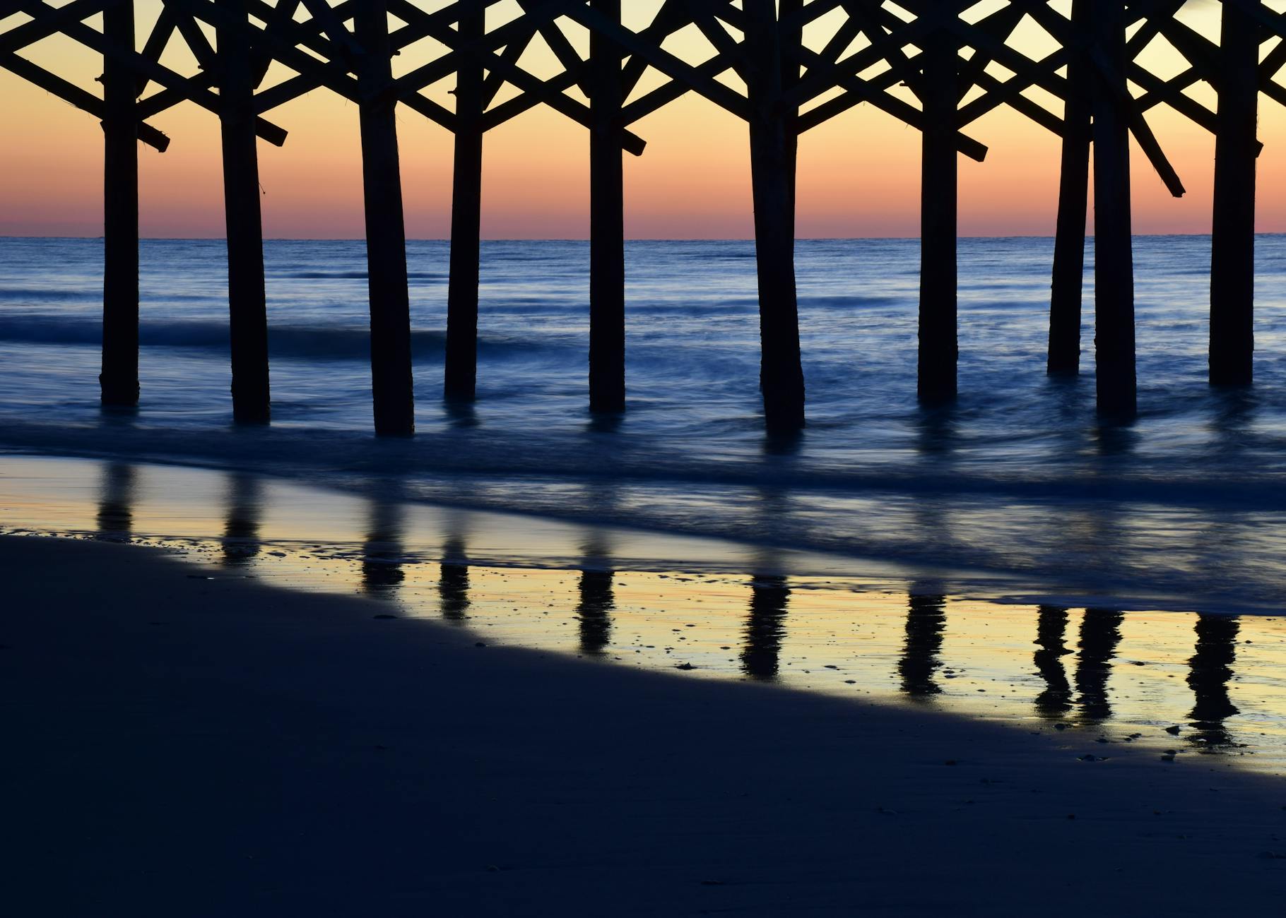 coast and wooden poles in the sea at dusk