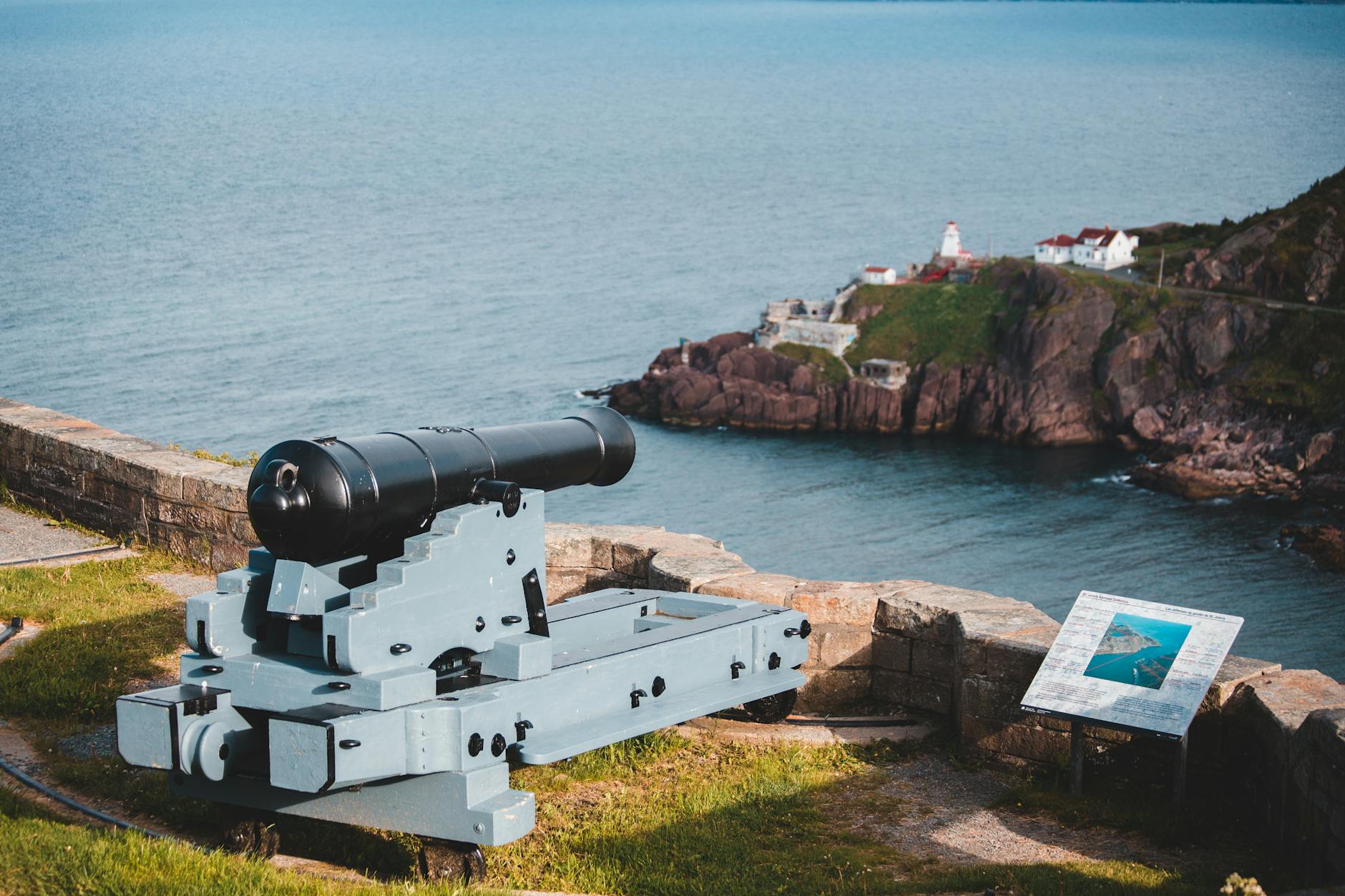 heavy metal cannon near coast with houses